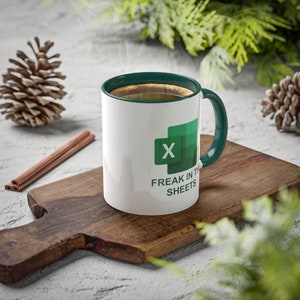 May include: White coffee mug with a green rim and handle. The mug has a green Microsoft Excel logo and the text "Freak in the sheets".