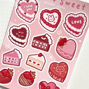 May include: A sheet of pink and red Valentine's Day stickers featuring various heart-shaped cakes and pastries with frosting, sprinkles, and cherries. The stickers say "I love you" and "Love".