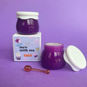 May include: Purple lip mask in a jar with a white lid and a small orange spoon. The jar is labeled "Taro Milk Tea Lip Mask".