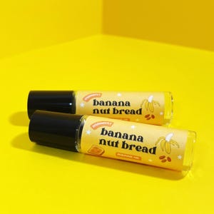 May include: Two yellow and black roll-on bottles with a label that reads "banana nut bread" and a small illustration of a banana, nuts, and coffee beans.