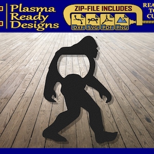 Peut inclure: Silhouette noire d'un Bigfoot ou d'un Sasquatch marchant, avec un ouvre-bouteille découpé dans son dos. L'image est sur un fond en bois.