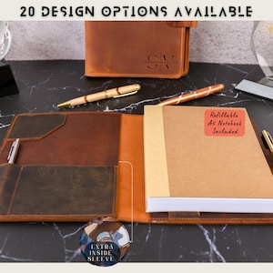 May include: A brown leather A5 notebook with a refillable notebook included. The notebook has an extra inside sleeve and a pen holder. The notebook is open to show the refillable notebook inside. The notebook is on a black marble surface.
