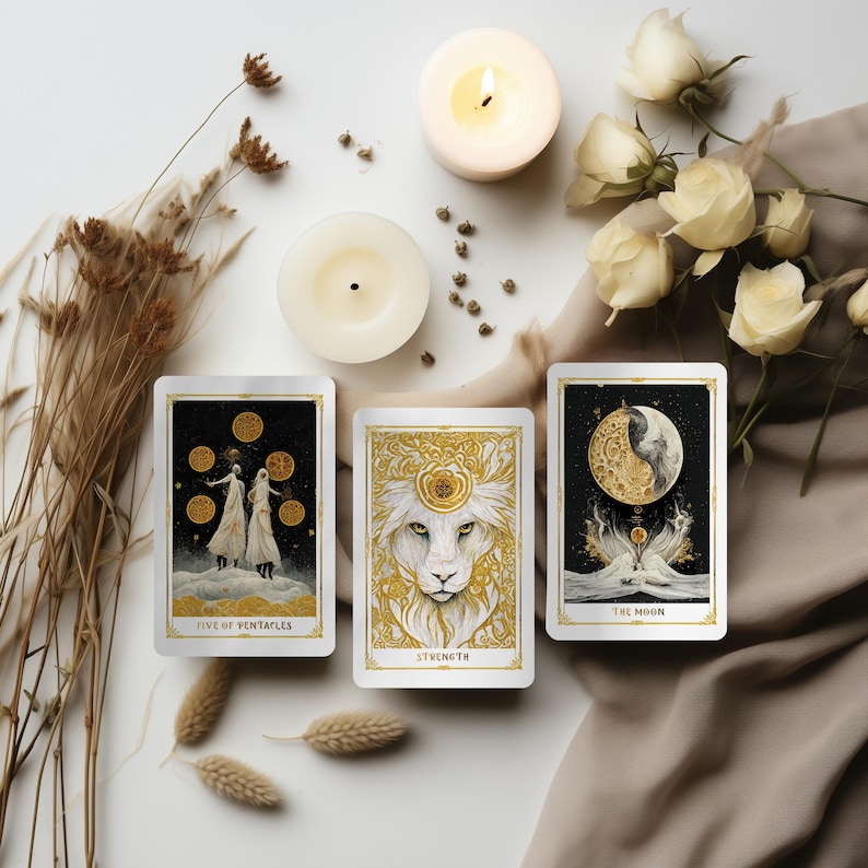 May include: Three tarot cards with gold and white designs are displayed, including "Five of Pentacles", "Strength", and "The Moon". The cards are arranged with candles, dried flowers, and white roses on a neutral-toned surface. The cards have gold borders.