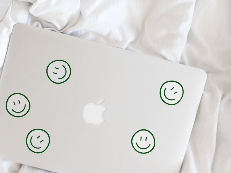 May include: A silver laptop computer with five green smiley face stickers on the lid.