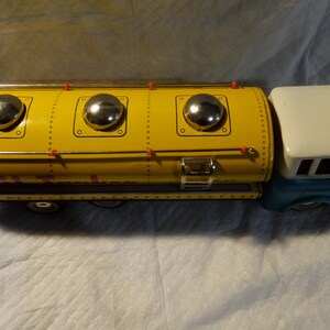 Pode incluir: Um caminh&atilde;o de brinquedo amarelo com uma cabine azul e um grande tanque amarelo. O tanque tem tr&ecirc;s detalhes circulares prateados no topo. O caminh&atilde;o &eacute; de metal e tem um visual vintage.