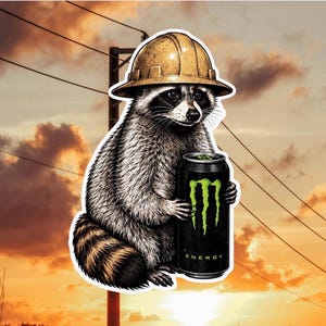 May include: A sticker featuring a raccoon wearing a yellow hard hat and holding a black energy drink can with a green claw logo and the text ENERGY printed on the bottom. The raccoon has grey and black fur with a striped tail and dark eye markings.