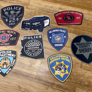 May include: A collection of nine assorted law enforcement and emergency service patches, including emblems for the El Mirage Police K9 Unit, Mesa Fire, Arizona State Gang Task Force, Hillsboro Police, Maricopa County Sheriff, NYPD, and California Highway Patrol.