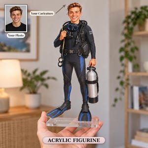 May include: A custom acrylic figurine depicting a smiling person in a black and blue scuba diving wetsuit, complete with a diving mask, oxygen tank, and fins. The figure stands on a clear rectangular base, featuring a photo-to-caricature conversion.