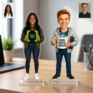 May include: Two custom acrylic standees featuring cartoon-style illustrations of a person in a green jacket holding a green bracket sign with the text HELLO WORLD and a person in a gray hoodie holding a mug with the text CODE COFFEE REPEAT.