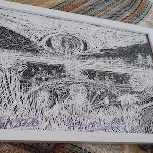 May include: A framed black and white ink drawing featuring a landscape with tall grasses, a body of water, and a large circular shape in the sky. The artwork includes the handwritten text "Highland Sacred" and "2026" in purple ink at the bottom.
