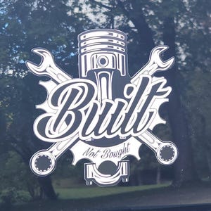May include: A white and black decal with the text "Built Not Bought" and a graphic of a piston and crossed wrenches. The decal also has the text "ErvDecals.com" in red and yellow.