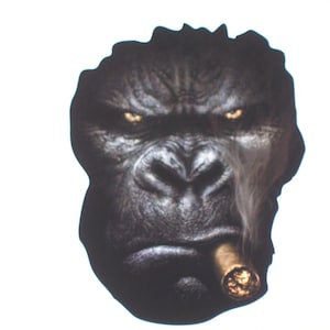 May include: A close-up of a gorilla's face with a serious expression. The gorilla is smoking a cigar. The background is white.