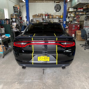 May include: Black Dodge Charger with yellow racing stripes and a New York number plate that reads "JPJ-4099".