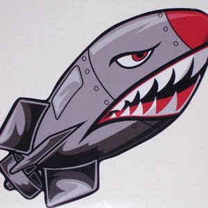 May include: A grey and red cartoon bomb with a shark mouth and teeth. The bomb has a red nose and a grey body with rivets.