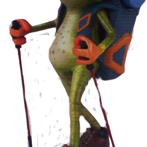 Puede incluir: Una rana verde con una mochila azul y botas de senderismo marrones, sosteniendo dos bastones de senderismo rojos.