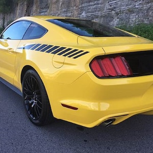 Peut inclure: Une Ford Mustang GT jaune avec des bandes de course noires et des jantes noires. La voiture a un pare-chocs arrière noir et une plaque d'immatriculation noire avec le texte "B800217".