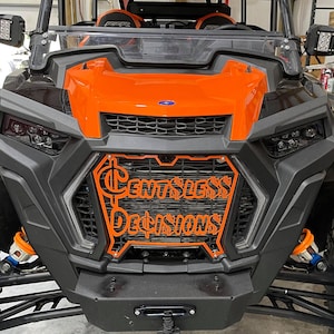 May include: Orange and black off-road vehicle with a custom grille that says "Cent$less Decisions".