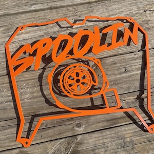 May include: Orange metal wall art featuring a stylized turbocharger with the word "SPOOLIN'" in a bold, handwritten font.