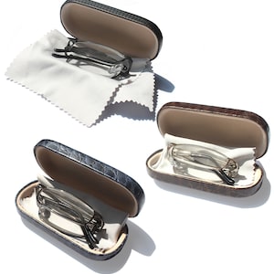 May include: Three pairs of reading glasses in cases. The cases are made of a faux leather material with a crocodile pattern. The glasses are in black, brown, and silver.