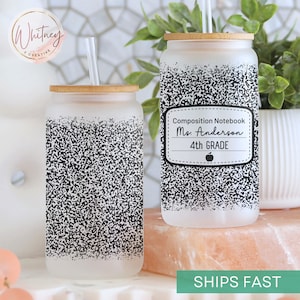 May include: Two frosted glass tumblers with bamboo lids and straws. The tumblers have a black and white speckled design. One tumbler has a label that reads "Composition Notebook Ms. Anderson 4th GRADE" with an apple icon.