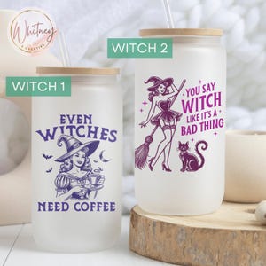 May include: Two frosted glass tumblers with a straw and a wooden lid. The tumbler on the left has a purple witch with a hat and the text "Even Witches Need Coffee". The tumbler on the right has a purple witch with a broom and the text "You Say Witch Like It's A Bad Thing".