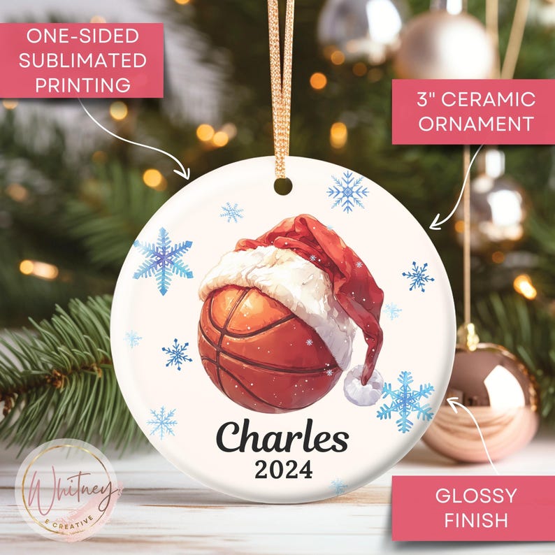 May include: A white ceramic Christmas ornament with a basketball wearing a Santa hat. The ornament is 3 inches in diameter and has a glossy finish. The text "Charles 2024" is printed on the ornament.