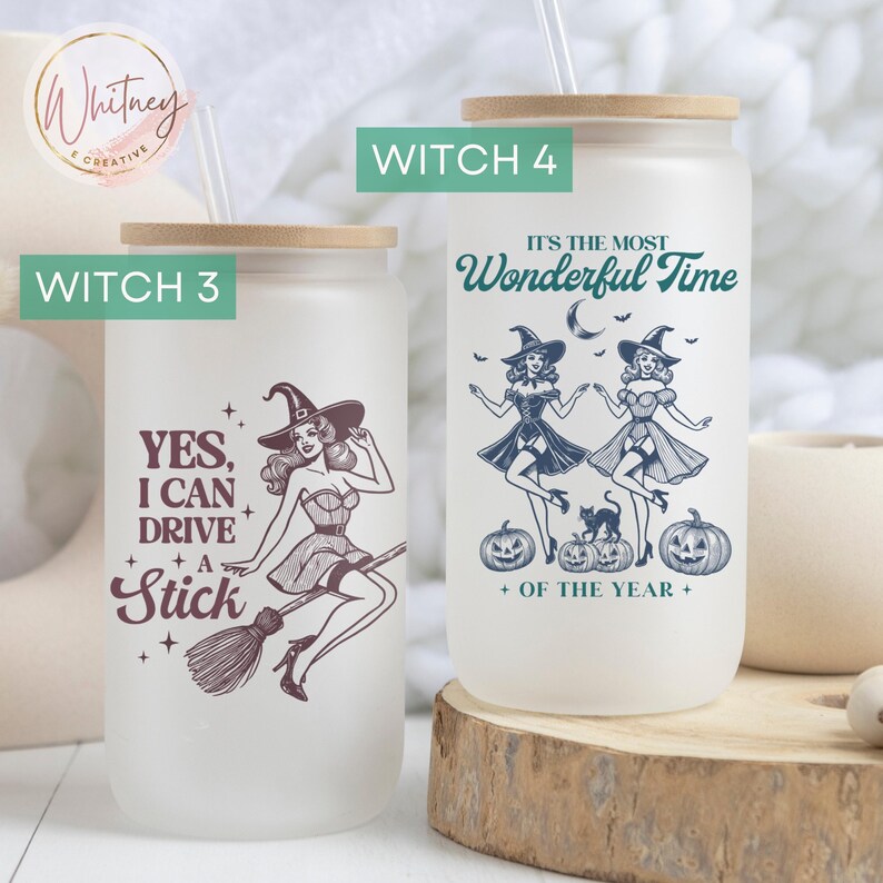 May include: Two frosted glass tumblers with a wood lid and straw. The tumbler on the left has a witch flying on a broomstick with the text "YES, I CAN DRIVE A STICK". The tumbler on the right has two witches dancing with the text "IT'S THE MOST WONDERFUL TIME OF THE YEAR".