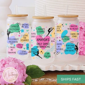 May include: Three clear glass tumblers with bamboo lids and straws. Each tumbler features colorful abstract shapes and motivational text for dancers, including "I Express Emotions", "I Radiate Elegance", and "I Master New Moves".