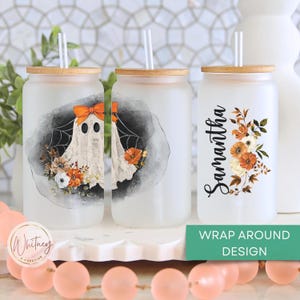 May include: Three frosted glass tumblers with bamboo lids and straws. The tumblers feature a ghost with a spiderweb, a floral design, and the name "Samantha". The tumblers are on a white surface with pink and orange beads.
