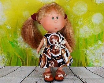 May include: A doll with blonde pigtails, green eyes, and a fair complexion. The doll wears a black and white dress with a coffee-themed pattern and brown shoes. The background is a yellow-green gradient with white dandelion illustrations.