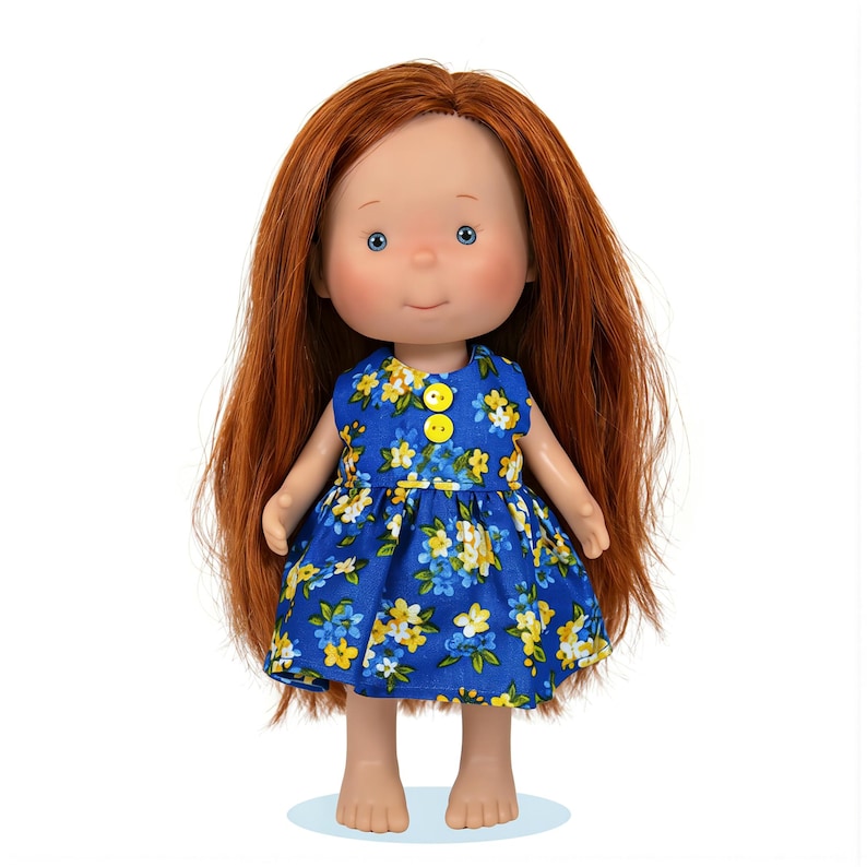 May include: A doll with red hair and blue eyes wearing a blue dress with yellow and white floral patterns. The dress has yellow buttons. The doll has a smiling expression.