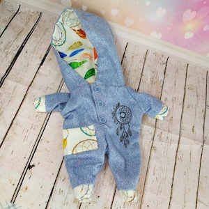 May include: A blue hooded baby onesie with a white and colorful dreamcatcher pattern on the hood and a black dreamcatcher design on the front. The onesie has a pocket on the front with a dreamcatcher pattern.