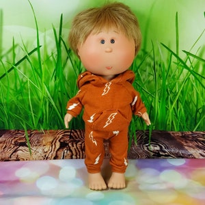 May include: A handmade doll with a round face, blonde hair, and large blue eyes. The doll is wearing a brown hoodie and matching pants with a white lightning bolt pattern.