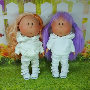 May include: Two dolls with white hooded sweatshirts and matching pants. One doll has orange hair and the other has purple hair.