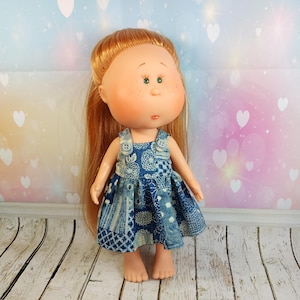Könnte beinhalten: Eine handgemachte Puppe mit langen, glatten, hellbraunen Haaren, die ein blaues und weißes Patchworkkleid mit einem Jeans-Lätzchen und Knöpfen trägt. Die Puppe hat ein rundes Gesicht mit Sommersprossen und grünen Augen.