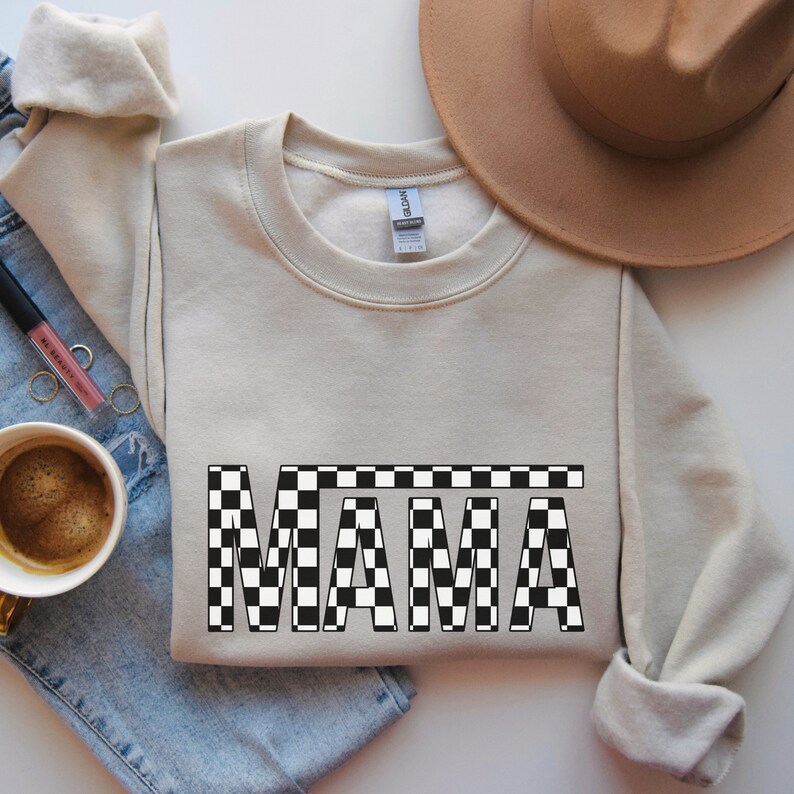 May include: A beige sweatshirt with a black and white checkered "MAMA" graphic.
