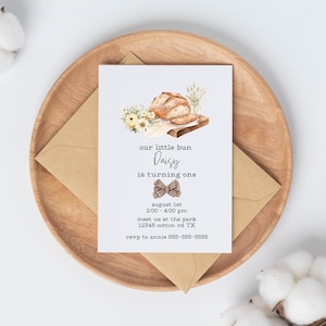 May include: A watercolor illustration of a loaf of bread on a cutting board with a bow tie and the text "our little bun Daisy is turning one" and party details.