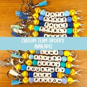 Pu&ograve; includere: Portachiavi a tema softball personalizzati con nomi. Ogni portachiavi presenta perline da softball gialle e bianche, perline con lettere e perline colorate. Il testo "CUSTOM TEAM ORDERS AVAILABLE" &egrave; visualizzato.