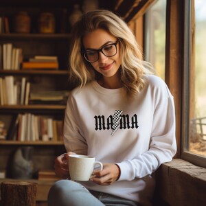 May include: White sweatshirt with a black and white checkered lightning bolt graphic and the text "MAMA" in a gothic font.