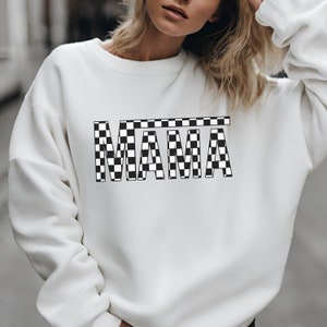 May include: White sweatshirt with a black and white checkered "MAMA" graphic.