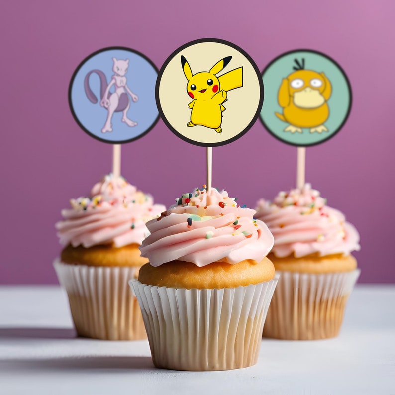 May include: Three pink frosted cupcakes with colorful sprinkles. Each cupcake has a round paper topper with a cartoon image of a Pokemon character. The toppers are Pikachu, Mewtwo, and Squirtle.