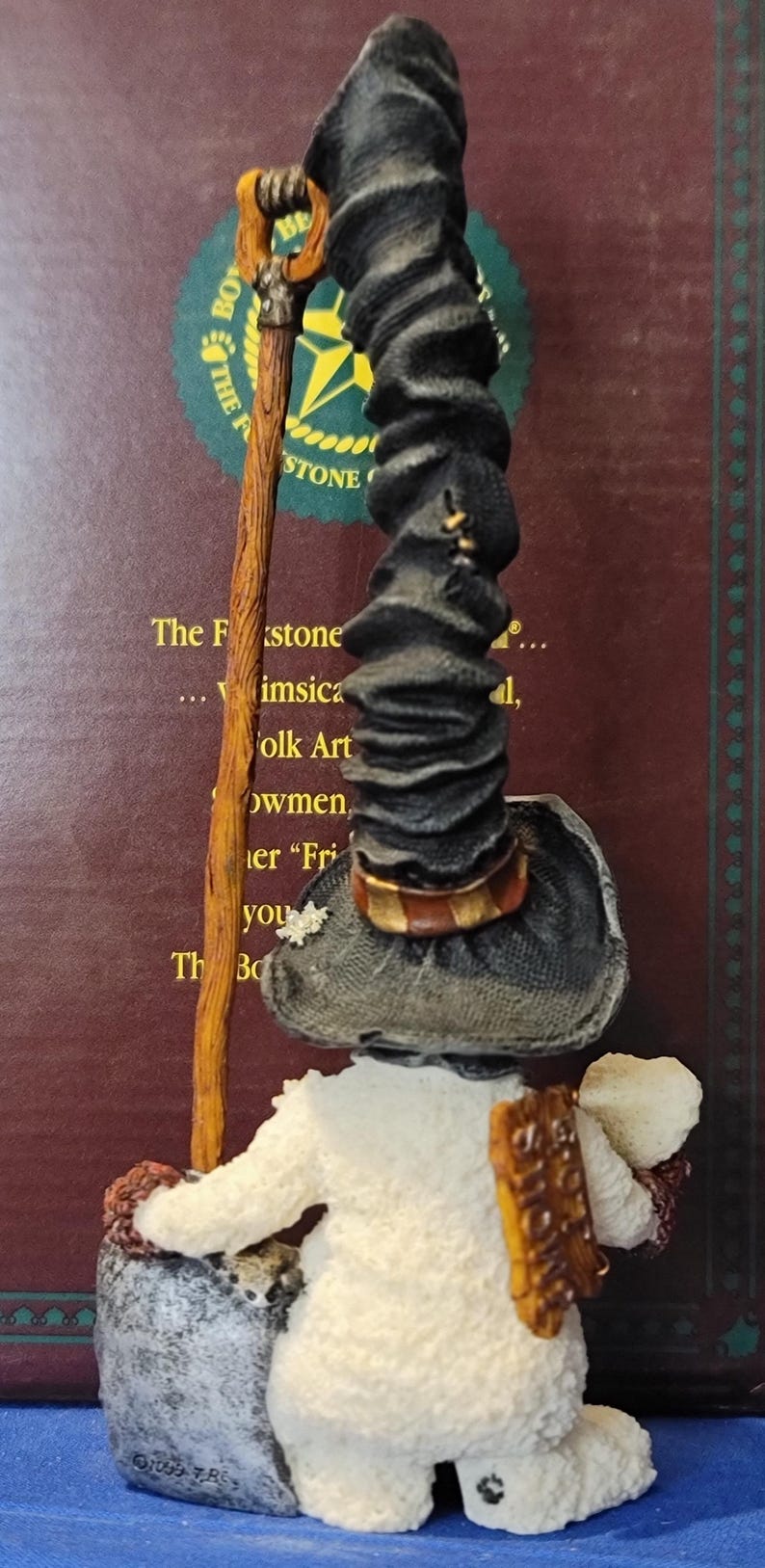 K&ouml;nnte beinhalten: Eine skurrile Schneemannfigur mit schwarzem Hut, die einen Wanderstock und einen Sack h&auml;lt. Der Schneemann hat einen wei&szlig;en K&ouml;rper und einen braunen Rucksack. Die Figur ist ein Volkskunstwerk.