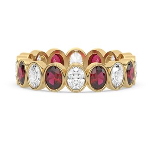 May include: A gold band ring with alternating oval-shaped ruby and diamond stones.