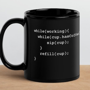 May include: Black coffee mug with white text that reads: "while(working){ while(cup.hasCoffee) sip(cup); } refill(cup); }"