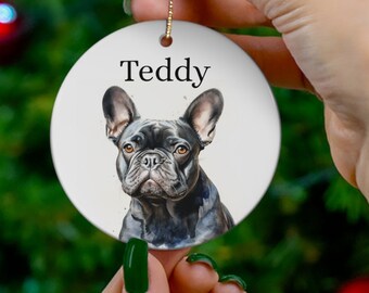 May include: A white ceramic Christmas ornament with a black French Bulldog illustration and the name "Teddy" printed on it.