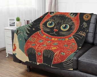 May include: A black cat wearing a red and gold patterned sweater sits on a cream and blue background. The cat has large blue eyes and a black nose. The background is filled with floral and geometric patterns.