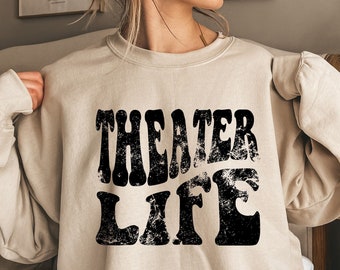May include: A beige sweatshirt with a black graphic that says "Theater Life" in a retro font.