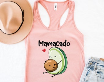 Può includere: Canotta rosa con una grafica di un avocado che tiene un avocado più piccolo con il testo "Mamacado" stampato sul davanti.