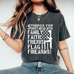 May include: A dark gray t-shirt with a white graphic that reads "5 things you don't mess with: family, faith, friends, flag, firearms". The graphic includes a stylized American flag and a rifle.