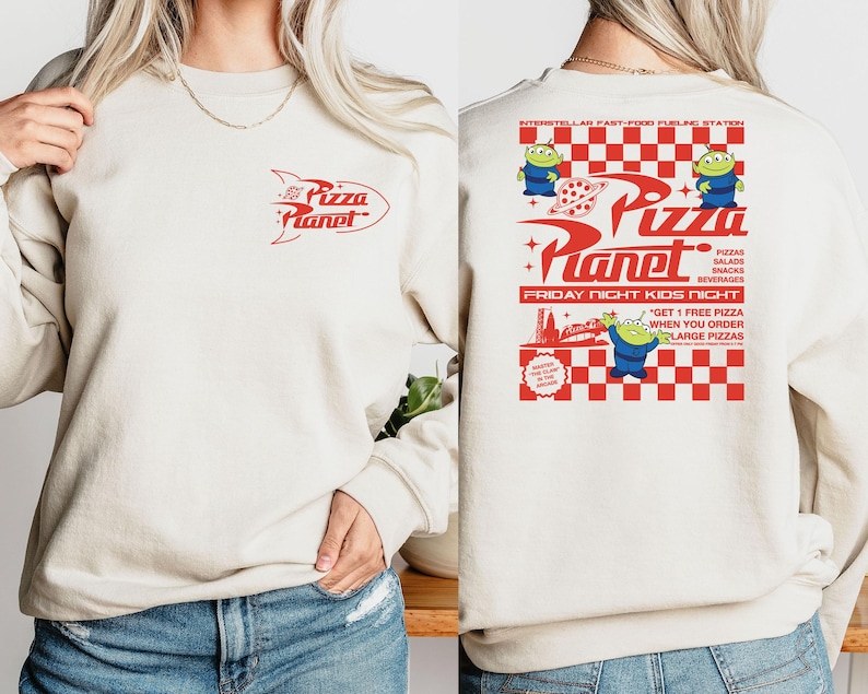 Peut inclure: Un sweat-shirt cr&egrave;me avec un motif rouge et blanc du logo Pizza Planet et le texte "Pizza Planet" et "Friday Night Kids Nicht". Le motif comprend &eacute;galement un motif &agrave; carreaux et des personnages d'extraterrestres de dessin anim&eacute;.